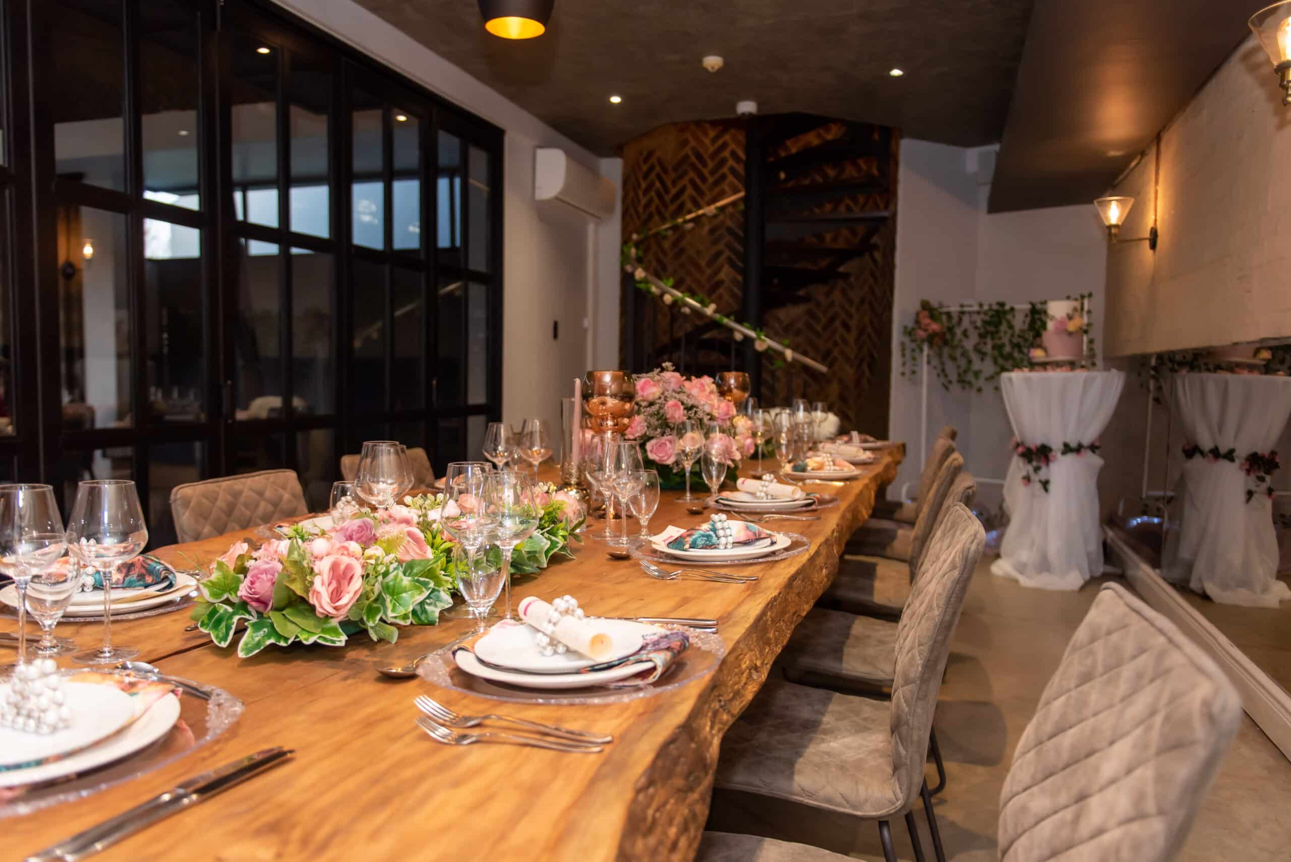 Dinner table with plates, glasses, cutlery, and flowers on it.